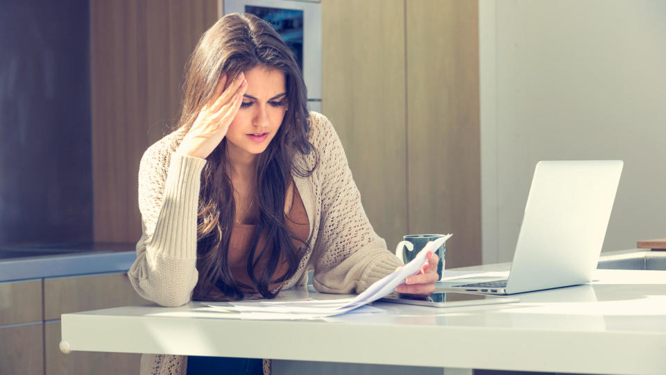 Woman doing paperwork with a laptop and digital tablet.