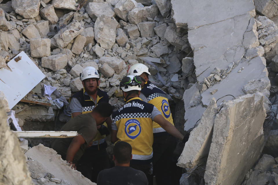 This photo provided by the Syrian Civil Defense White Helmets, which has been authenticated based on its contents and other AP reporting, shows Syrian White Helmet civil defense workers search for victims from under the rubble of a destroyed building that hit by Syrian government and Russian airstrikes, in the northern town of Maaret al-Numan, in Idlib province, Syria, Monday, July 22, 2019. Syrian opposition activists say an airstrike on a busy market in a rebel-held town in northwestern Syria has killed at least 16 people. (Syrian Civil Defense White Helmets via AP)