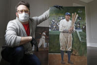 In this April 29, 2020, photo, baseball artist Graig Kreindler poses with his unfinished painting of Babe Ruth, right, as a painting of Josh Gibson rests behind him at his residence in the Brooklyn borough of New York. Over 200 of Kreindler's paintings of Negro Leagues players were on exhibit at the Negro Leagues Baseball Museum in Kansas City, Mo., when the coronavirus pandemic caused the museum to close. (AP Photo/Kathy Willens)