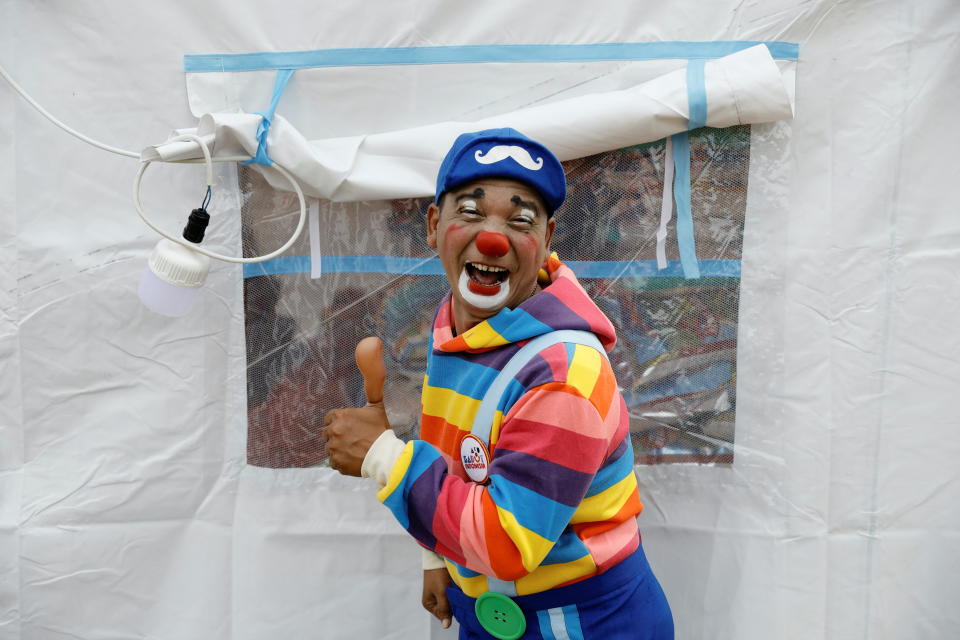 Dedy Rachmanto, 53, known as Dedy Delon who is the founder of a clowns' association named Aku Badut Indonesia or 'I Indonesia Clown', poses for a picture outside a temporary tent after performing a show to bring cheers to children who were affected by the eruption of Mount Semeru volcano, at a temporary shelter in Penanggal, Candipuro district, Lumajang, East Java province, Indonesia, December 9, 2021. REUTERS/Willy Kurniawan REFILE- QUALITY REPEAT     TPX IMAGES OF THE DAY