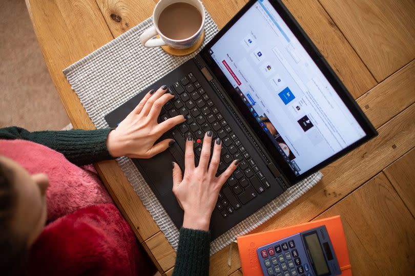 a woman using a laptop on a dining room table set up as a remote office to work from home