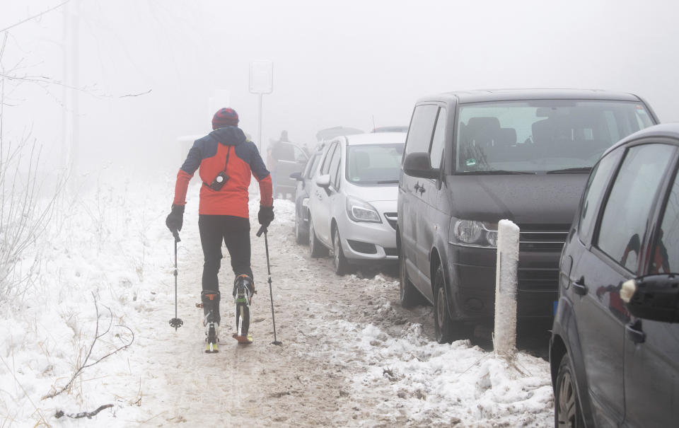A cross-country skier passes illegally parked vehicles on highway 401 at Nienstedt, Germany, Tuesday, Jan. 5, 2020 Overcrowded parking spaces in snowy regions became a problem during the lockdown. (Julian Stratenschulte/dpa via AP)