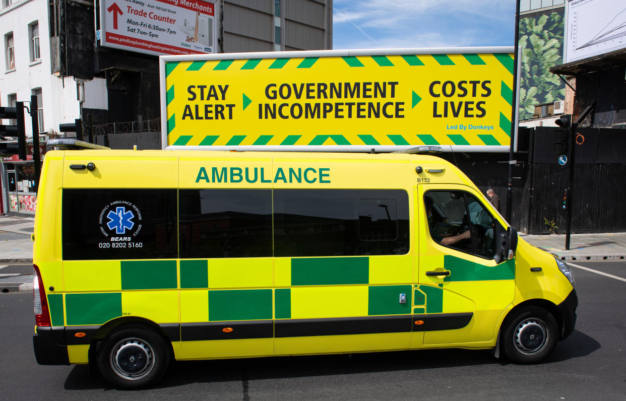 An ambulance passes a billboard by campaign group Led by Donkeys parodying an official government coronavirus message campaign, in central London, after the introduction of measures to bring the country out of lockdown. (Photo by Dominic Lipinski/PA Images via Getty Images)