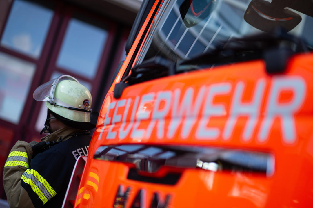 Eine Einsatzkraft der Feuerwehr steht neben einem Einsatzfahrzeug. (Symbolbild: Marijan Murat/dpa)