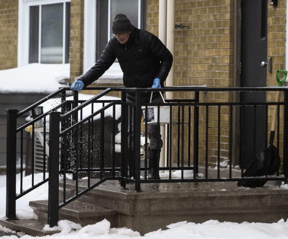 A person lays down salt outside an apartment complex in Ottawa, as a winter storm warning is in effect, on Friday, Dec. 23, 2022. (Justin Tang/The Canadian Press via AP)
