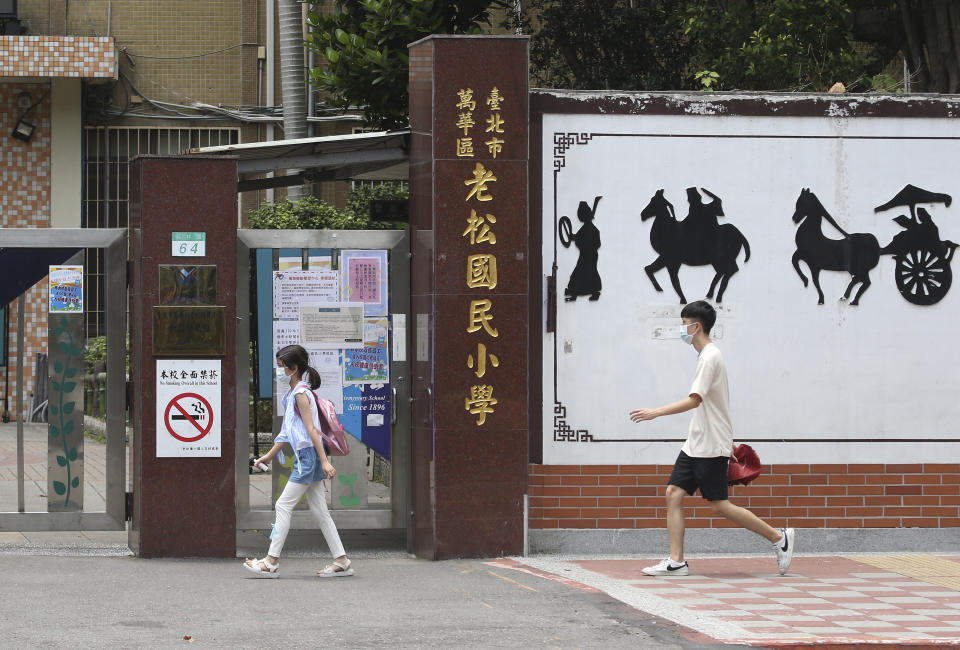 Students wearing face masks to protect against the spread of the coronavirus walk past a closed primary school after the COVID-19 alert raise to level 3 in Taipei, Taiwan, Tuesday, May 18, 2021. (AP Photo/Chiang Ying-ying)