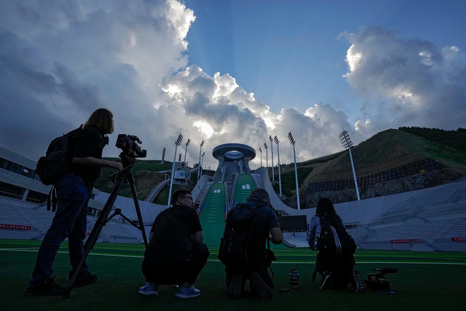 Journalists film the National Ski Jumping Centre, one of the venues for Beijing 2022 Olympic and Paralympic Winter Games, during a media tour in Zhangjiakou in northwestern China's Hebei province on Wednesday, July 14, 2021. (AP Photo/Andy Wong)