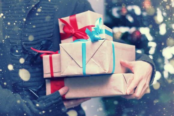 Holiday shopper holding wrapped gifts.