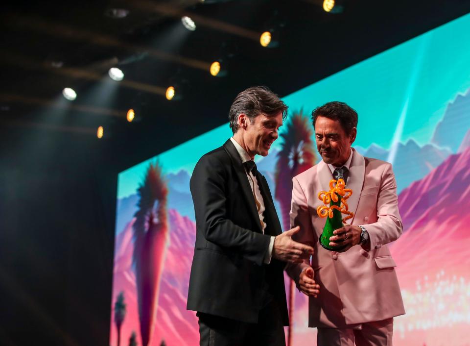 Robert Downey Jr. hands the Desert Palm Achievement Award over to "Oppenheimer" actor Cillian Murphy as they exit the stage together during the Palm Springs International Film Awards in Palm Springs, Calif., Thursday, Jan. 4, 2024.