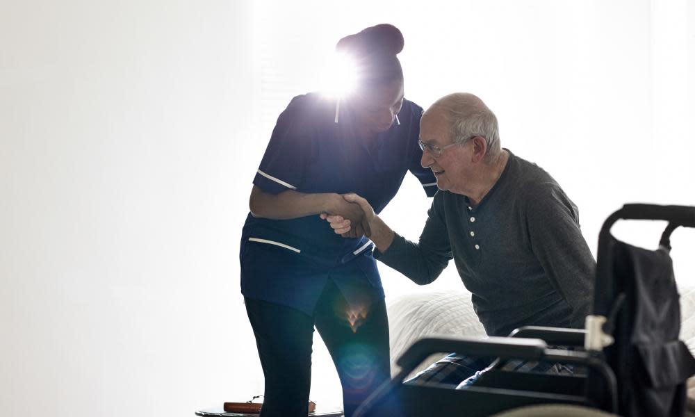 Female nurse helping senior man get up from bed at home