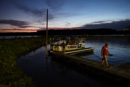 Captain Nate Wallick's clients, six regulars of his from Michigan, disembark after a six-hour day out hunting Asian carp with bow and arrow on the Illinois River near Lacon
