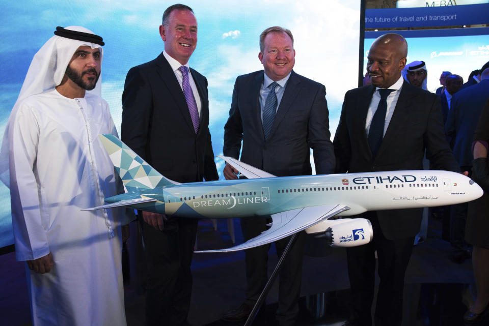 Etihad COO Mohammad al-Bulooki, left, Etihad CEO Tony Douglas, second left, Boeing Commercial Airplanes president and CEO Stanley A. Deal, third left, and Boeing Global Services President and CEO Ted Colbert, right, pose in front of a Boeing 787 Dreamliner model at the Dubai Airshow in Dubai, United Arab Emirates, Monday, Nov. 18, 2019. Abu Dhabi's flagship carrier Etihad said Monday it had partnered with Boeing Co. to launch what they say will be one of the world's most fuel-efficient long haul airplanes as the company seeks to save costs on fuel and position itself as a more environmentally-conscious choice for travelers. (AP Photo/Jon Gambrell)