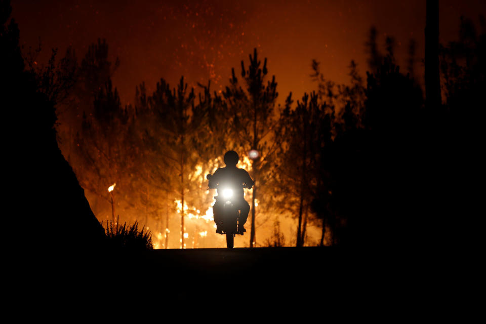 A firefighter rides a motorbike away from the fire&nbsp;around&nbsp;the village of Macao, near Castelo Branco, Portugal, on July 26, 2017. (Photo: Rafael Marchante / Reuters)