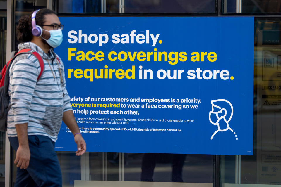 NEW YORK, NEW YORK - SEPTEMBER 30: A man wearing a  mask walks past a &quot;shop safely as the city continues , face covers are required in our store&quot; sign outside a Best Buy in Union Square Phase 4 of re-opening following restrictions imposed to slow the spread of coronavirus on September 30, 2020 in New York City. The fourth phase allows outdoor arts and entertainment, sporting events without fans and media production. (Photo by Alexi Rosenfeld/Getty Images)