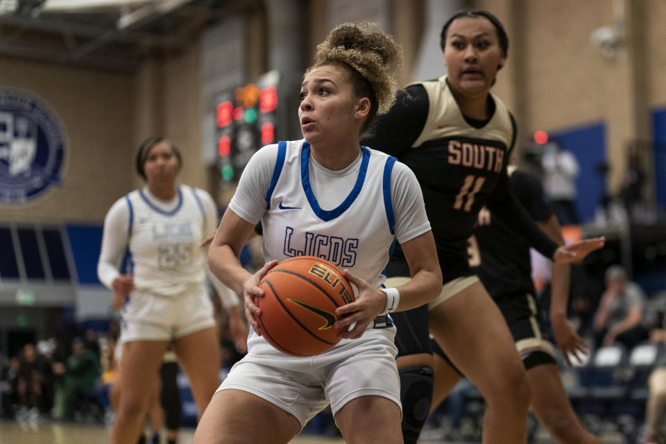 La Jolla Country Day high school point guard Jada Williams, center, drives to the basket during a basketball game Friday, Nov. 18, 2022, in Chatsworth, Calif. Williams’ videos of crazy basketball shots first got her noticed on social media and ultimately led to endorsement deals. (AP Photo/Gregory Bull)