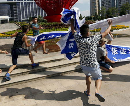 Men (2nd and 3rd from L) whom animal right activists believe to be plain clothes policemen, snatch placards from activists in front of a city hall in Yulin, Guangxi Autonomous Region, June 22, 2015, during a protest against the local dog meat festival. REUTERS/Kim Kyung-Hoon