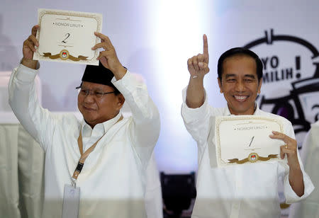 Indonesian President Joko Widodo (R) and his opponent in next year's presidential elections Prabowo Subianto, a retired special forces commander, hold their ballot numbers during a ceremony at the election commission headquarters in Jakarta, Indonesia, September 21, 2018. REUTERS/Darren Whiteside