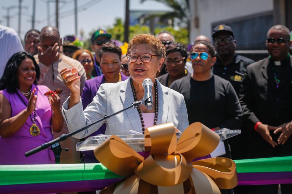 A person speaks in front of a microphone at the lectern, with people behind them, outdoors.