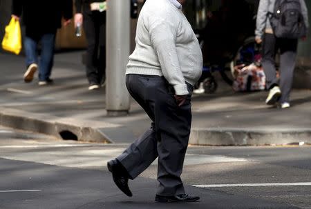 A man crosses a main road as pedestrians carrying food walk along the footpath in central Sydney, Australia, in this August 12, 2015 file photo. REUTERS/David Gray/Files