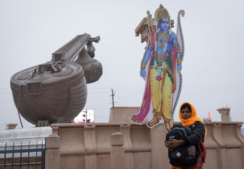 A Hindu devotee carries her bag as she walks past a cut-out of Lord Ram on a street, ahead of the opening of the temple of Lord Ram, in Ayodhya
