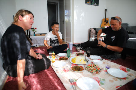 Afghan migrant Ali Mohammad Rezaie and his German friends Chris and Jochen eat together in his flat in Berlin, Germany, September 29, 2018. REUTERS/Hannibal Hanschke