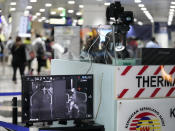 Health officials watch travelers on a thermographic monitor at the Kuala Lumpur International Airport in Sepang, Malaysia, Tuesday, Jan. 21, 2020. Countries both in the Asia-Pacific and elsewhere have initiated body temperature checks at airports, railway stations and along highways in hopes of catching those at risk of carrying a new coronavirus that has sickened more than 200 people in China. (AP Photo/Vincent Thian)