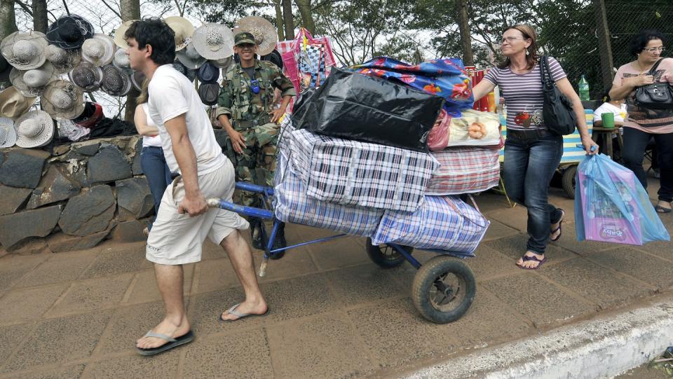 Brazilians carrying goods bought in Ciudad del Este approach the Friendship Bridge, which links the Paraguayan city with Foz do Iguacu, Brazil, in 2010. <a href="https://www.gettyimages.com/detail/news-photo/brazilians-carry-goods-they-bought-in-ciudad-del-este-as-news-photo/106896478?adppopup=true" rel="nofollow noopener" target="_blank" data-ylk="slk:Norberto Duarte/AFP via Getty Images;elm:context_link;itc:0;sec:content-canvas" class="link ">Norberto Duarte/AFP via Getty Images</a>