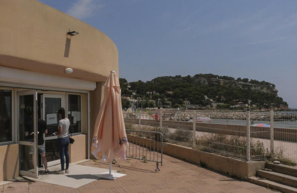 FILE - In this Friday, July 23, 2021, file photo, people enter a vaccination center at the beach in Carry-le-Rouet, southern France. Europe’s famed summer holiday season is in full swing, but efforts to inoculate people against coronavirus are not taking a break. From France’s Mediterranean coast to Italy’s Adriatic beaches, health authorities are trying to make a COVID-19 shot as much a part of this summer as sunscreen and shades.(AP Photo/Nicolas Garriga, File)