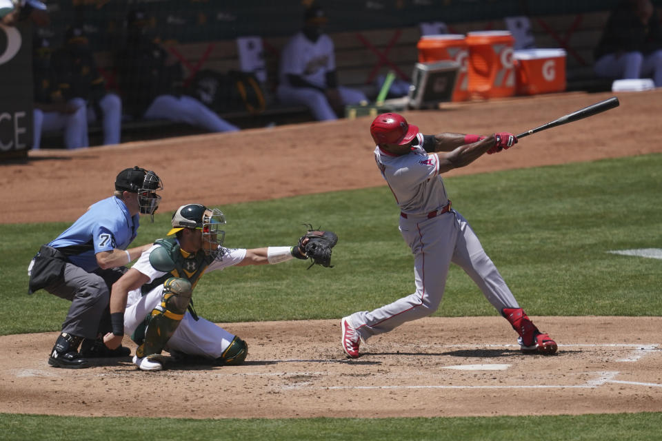 Los Angeles Angels' Justin Upton, right, hits a solo home run in front of Oakland Athletics catcher Austin Allen and umpire Mike Muchlinski (76) during the fourth inning of a baseball game in Oakland, Calif., Saturday, July 25, 2020. (AP Photo/Jeff Chiu)