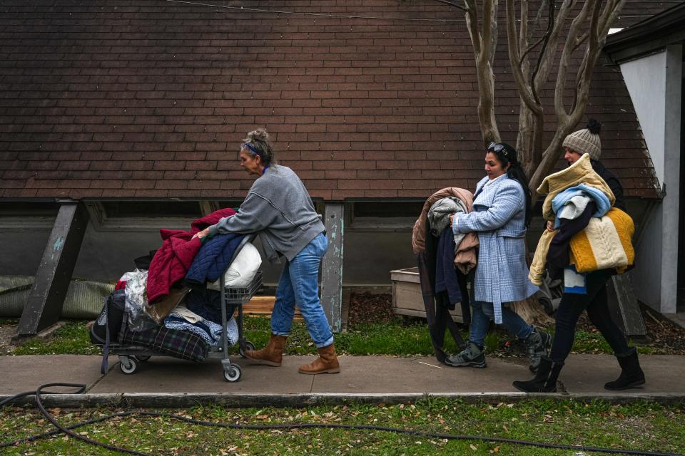 From left, Shelter Services Program Manager Kelly Jura-Myrick, Mobile Ambassador Carmen Abdelhadi, and volunteer Tara McLeod carry jackets and blankets out of the Sunrise Homeless Navigation Center on Sunday, Jan. 14, 2024. All of the items are being delivered to homeless Austin residents ahead of freezing weather.