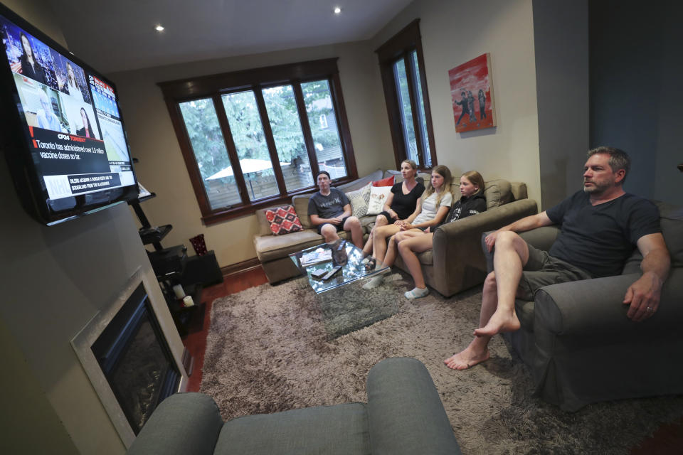 The Wood family, from left, Ethan, Amanda, Lola, Ruby and David, watch television at home in Toronto, Canada, on Monday, July 12, 2021. With nearly 70% of its adult population receiving at least one dose of a COVID-19 vaccine, Canada has the world's highest vaccination rate and is now moving on to immunize children, who are at far lower risk of coronavirus complications and death. (AP Photo/Kamran Jebreili)