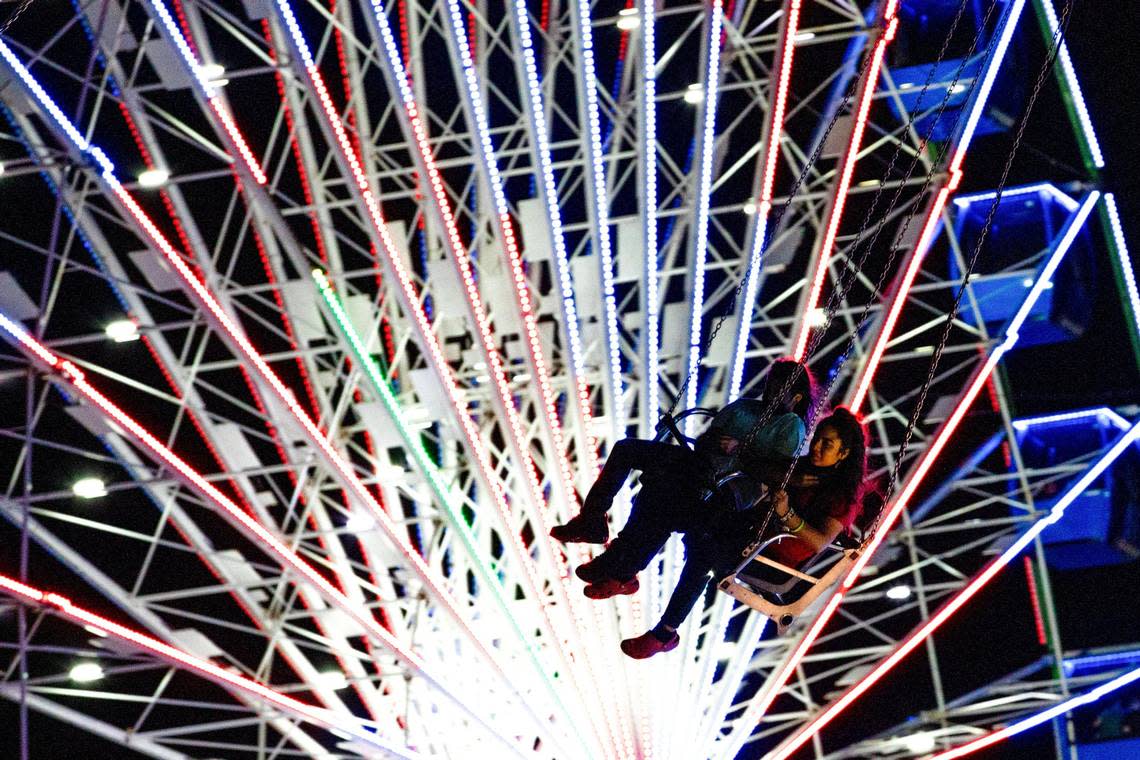 Patrons enjoy the swing ride as the Ferris Wheel spins in the background at Santa’s Enchanted Forest in Hialeah. Daniel A. Varela/dvarela@miamiherald.com