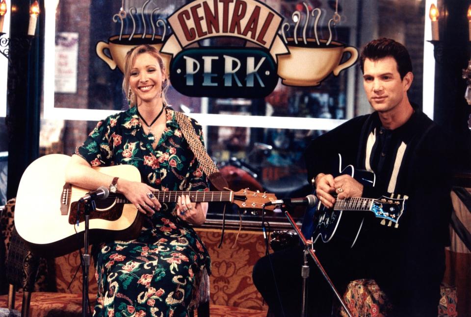 Phoebe and guest playing guitars in Central Perk from "Friends." Phoebe wears a bohemian style dress