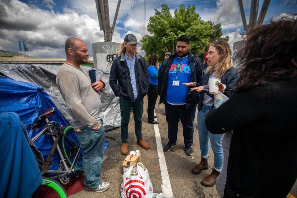 Raman aides and outreach workers with the non-profit PATH talk to Christopher Given in May 2023 along the L.A. River.