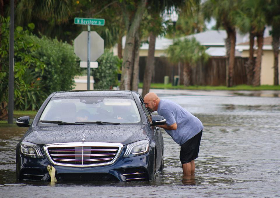 Melvin Juarbe attempts to assist an unidentified driver whose car stalled in floodwaters from Hurricane Helene on Thursday. ((Max Chesnes/Tampa Bay Times via AP))