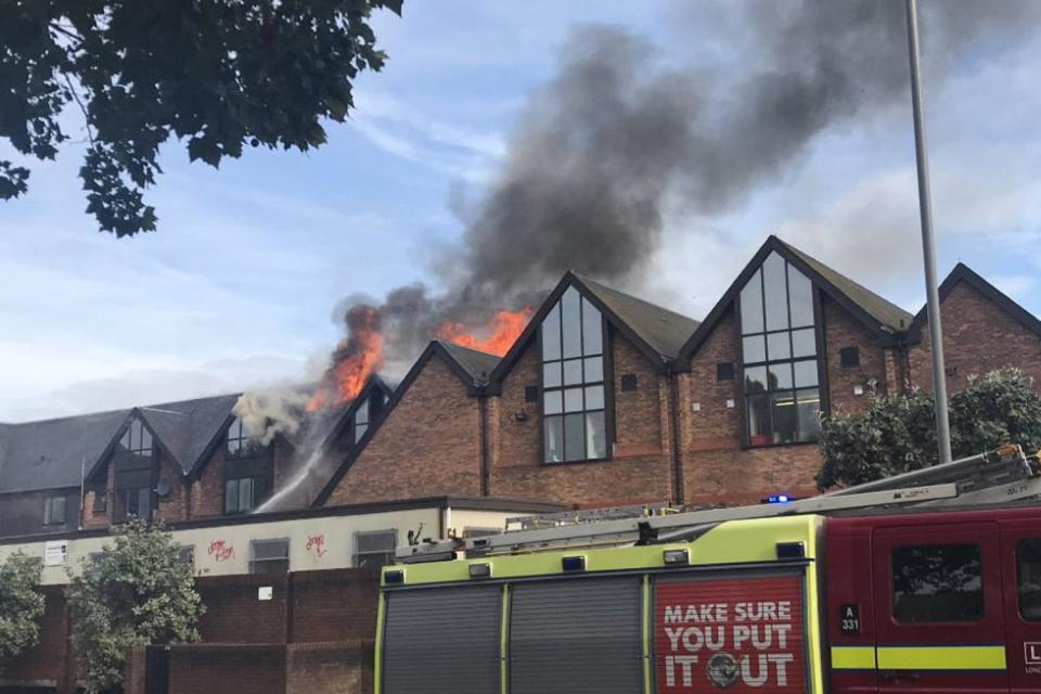 Orange flames are seen eurpting from the roof of the building (@MartinBelam)