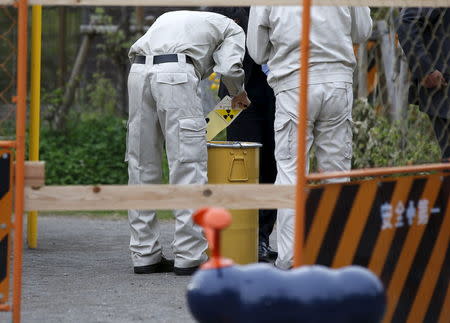 A worker of Tokyo's Toshima ward office puts a sticker on a container holding a fragment of an unknown object after it was dug up from the ground near playground equipment at a park in Toshima ward, Tokyo April 24, 2015. REUTERS/Toru Hanai