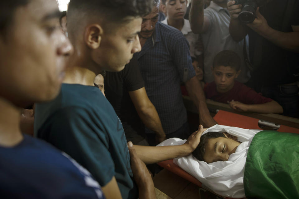 Relatives of Palestinian Omar al-Nile, 12, who was shot on Saturday during a violent demonstration on the eastern border between Gaza and Israel, mourn over his body during his funeral in Gaza City, Saturday, Aug. 28, 2021. (AP Photo/Khalil Hamra)