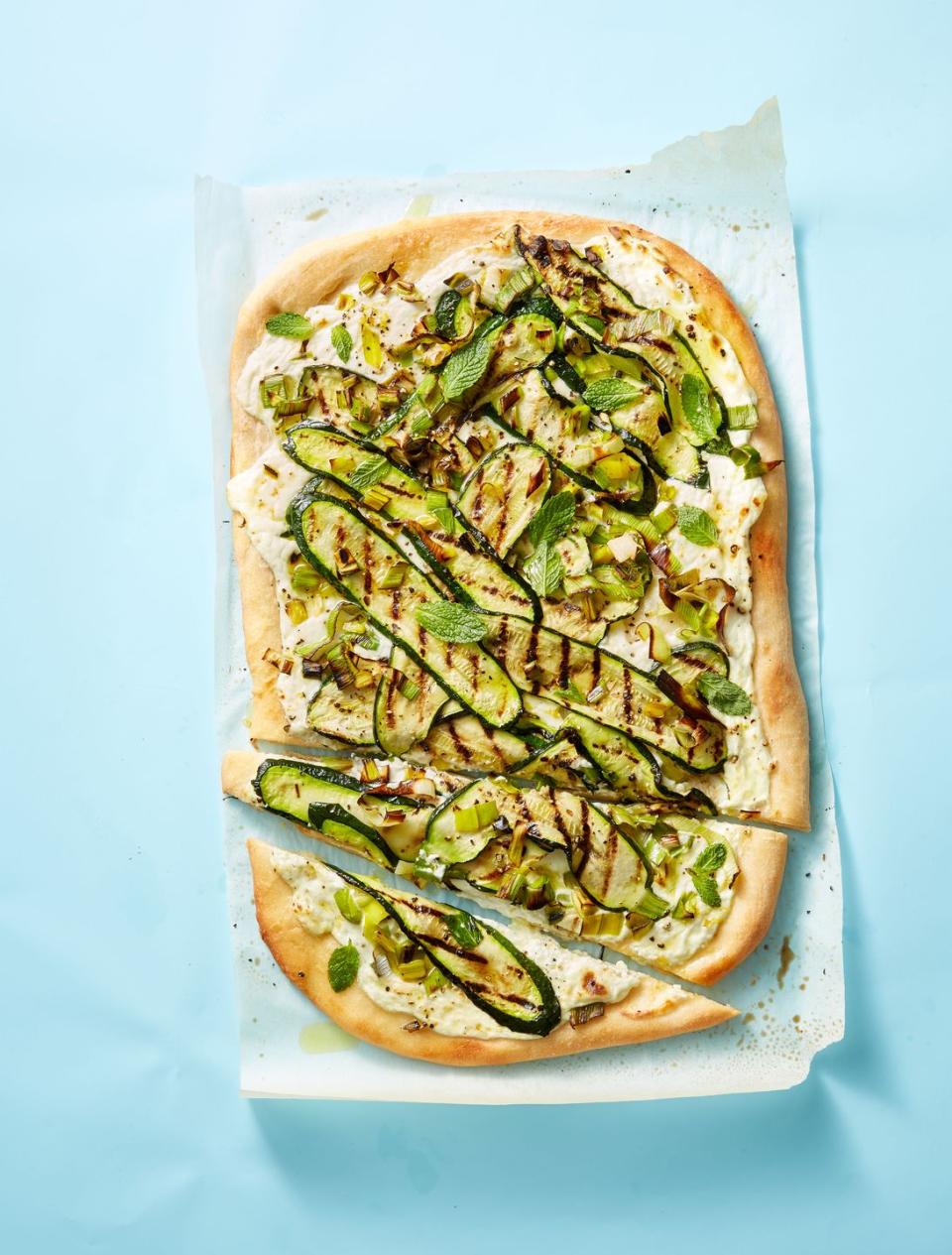 grilled leek, zucchini, and ricotta pizza on a piece of parchment paper