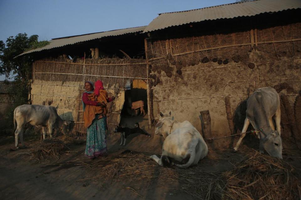 In this photo Nov 30, 2016 photo, a Nepalese woman carries her grandchild, whose father is working abroad as an unskilled laborer, in front of their home in Belhi village, in Saptari district, Nepal. The number of Nepali workers going abroad has more than doubled since the country began promoting foreign labor in recent years: from about 220,000 in 2008 to about 500,000 in 2015. Yet the number of deaths among those workers has risen much faster in the same period. In total, over 5,000 workers from this small country have died working abroad since 2008, more than the number of U.S. troops killed in the Iraq War. (AP Photo/Niranjan Shrestha)