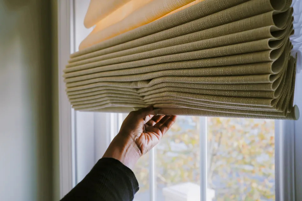 Close-up of unrecognizable black woman adjusting Roman shade on window