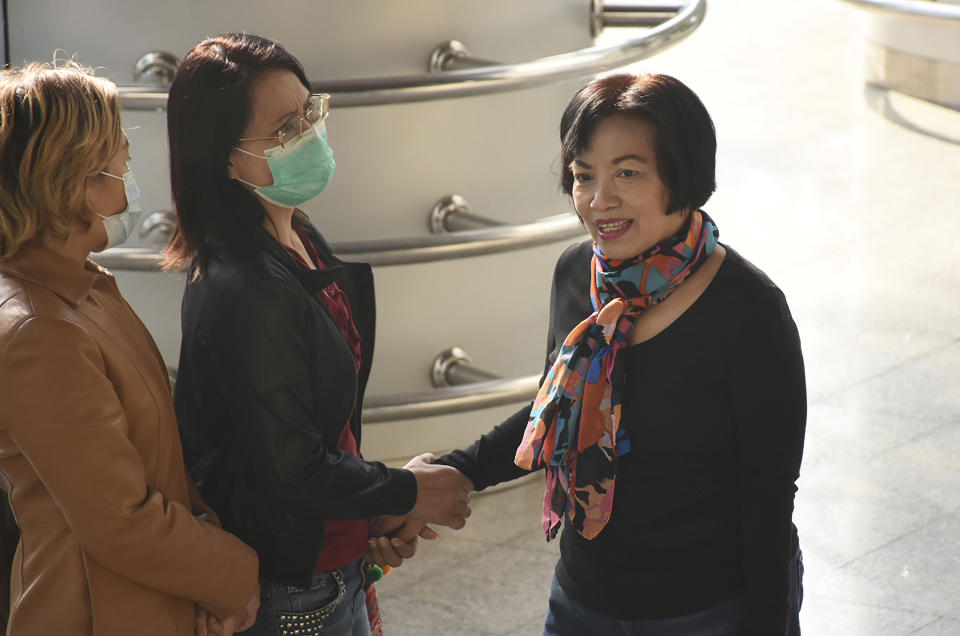 A woman identified only by her first name Anchan, right, shake hand with a friend as she arrives at the Bangkok Criminal Court in Bangkok, Thailand, Tuesday, Jan. 19, 2021. A court in Thailand on Tuesday sentenced a retired civil servant to a record 43.5 years in prison for insulting the monarchy by posting audio clips online of comments critical of the royal institution. (AP Photo)