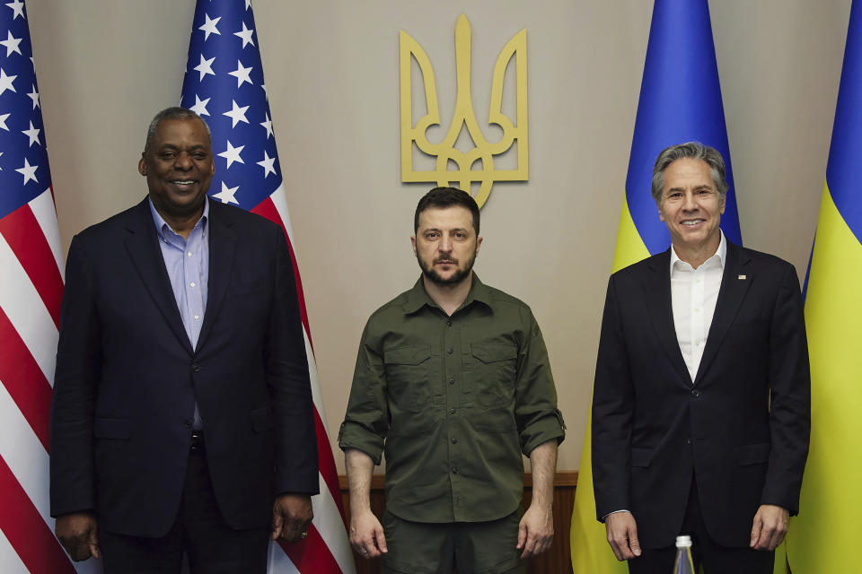 Lloyd Austin, Volodymyr Zelensky and Antony Blinken stand in front of American and Ukrainian flags.