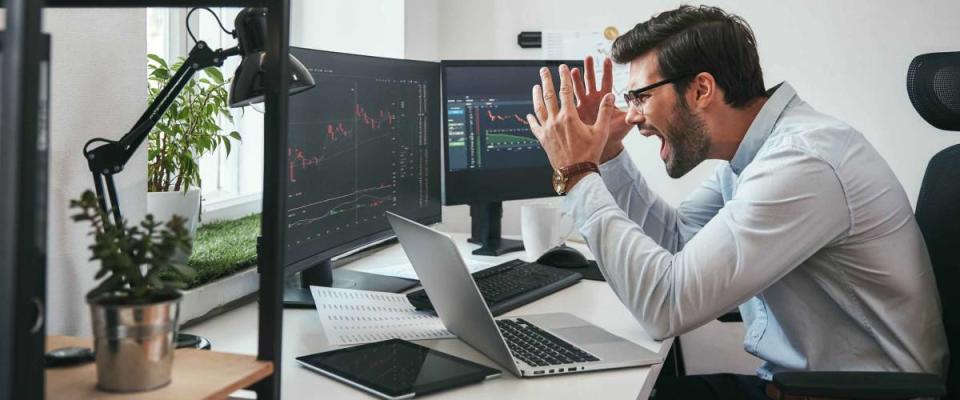 Failing! Frustrated young businessman or trader in formalwear is shouting and feeling angry while looking at trading charts and financial data in the office.