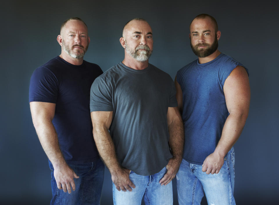 Three bearded men in blue standing next to one another