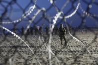 U.S. Border Patrol agents are seen though the border structure from the Mexican side at the Pacific Ocean, Tijuana, Mexico, Friday, Nov. 16, 2018. As thousands of migrants in a caravan of Central American asylum-seekers converge on the doorstep of the United States, what they won't find are armed American soldiers standing guard. (AP Photo/Rodrigo Abd)