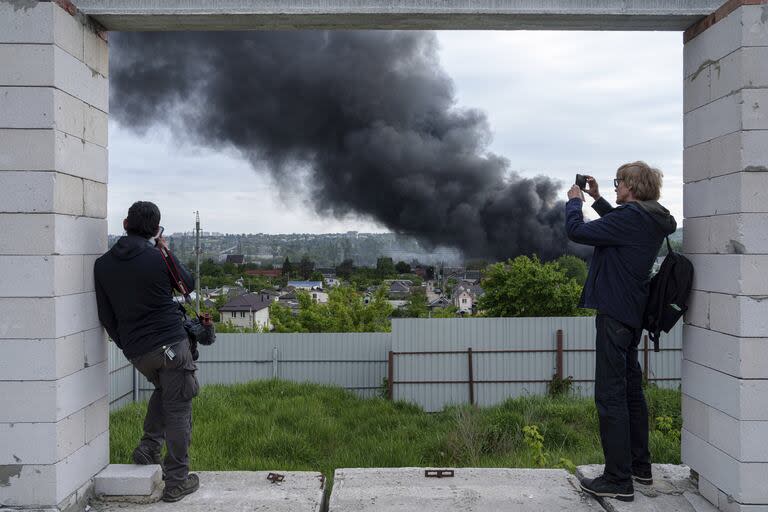 Periodistas extranjeros observan una estela de humo en Kharkiv, Ucrania, luego de un ataque ruso (AP Photo/Evgeniy Maloletka)