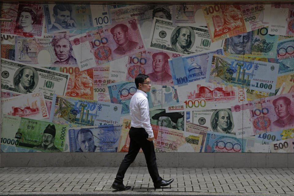 FILE - In this June 10, 2019, file photo, a man walks past a money exchange shop decorated with different banknotes at Central, a business district of Hong Kong. In a report released Wednesday, Sept. 25, 2019, the Asian Development Bank says that escalating trade tensions will sap Asian economies of some of their potential in this year and the next. (AP Photo/Kin Cheung, File)