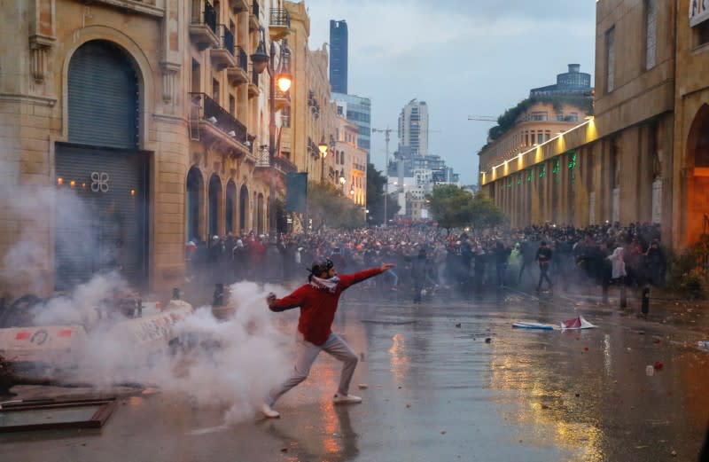 FILE PHOTO: A demonstrator throws a tear gas canister during a protest against a ruling elite accused of steering Lebanon towards economic crisis in Beirut