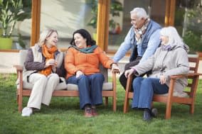 Senior friends sitting together in front of their retirement community house.